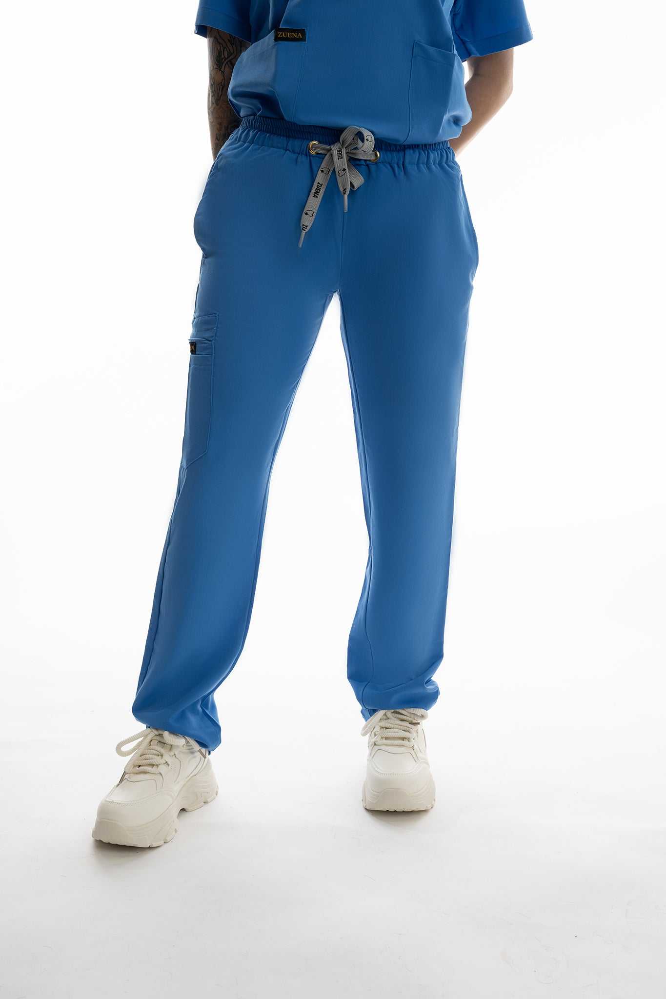 Person wearing blue scrubs with a white background