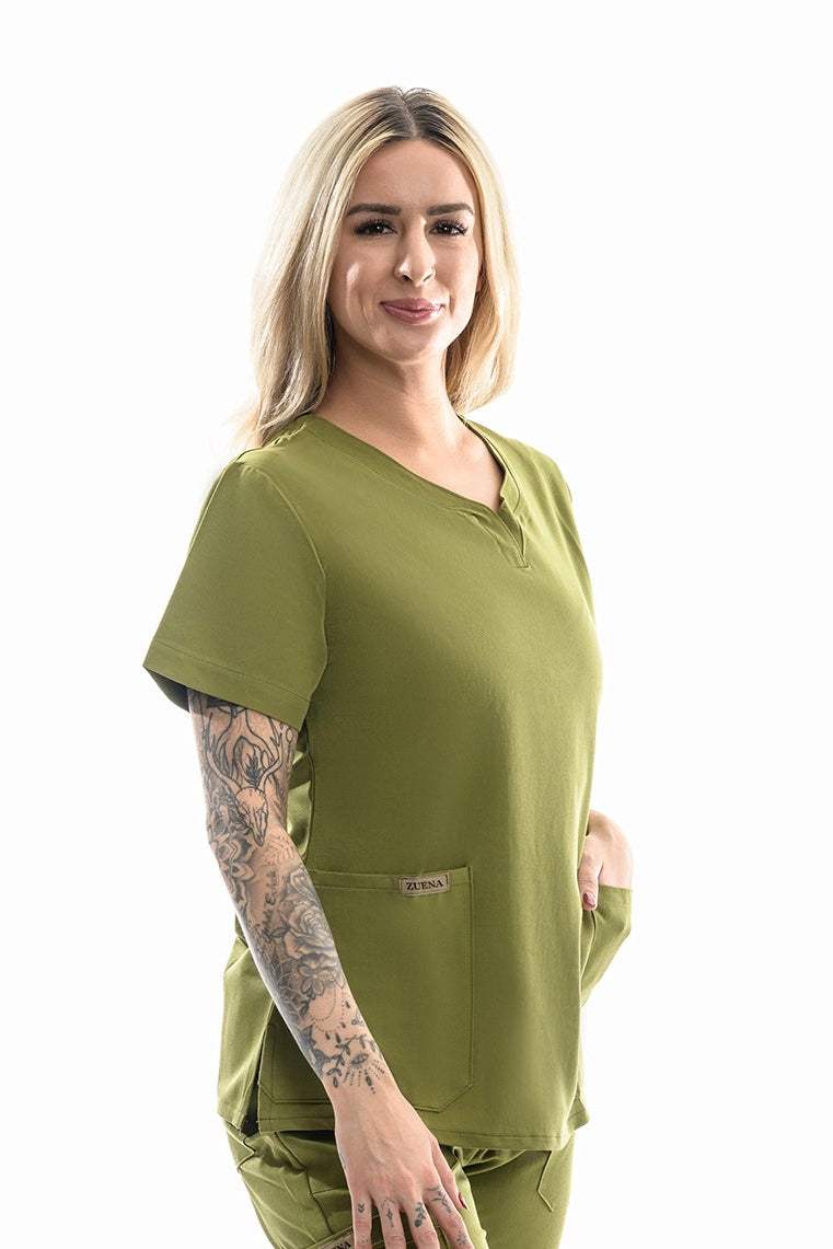 Woman wearing Zuena Olive Groove olive green scrub top with curved neck, short sleeves, three pockets, and side vents