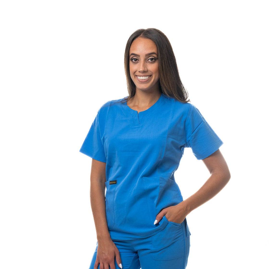 Woman wearing blue Skyward Bound Scrub Top with curved neck, short sleeves, three pockets, and side vents