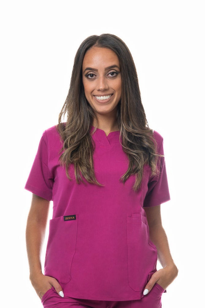 Woman wearing Zuena Rose Petal Scrub Top with curved neck, short sleeves, three pockets, and side vents in rose pink color