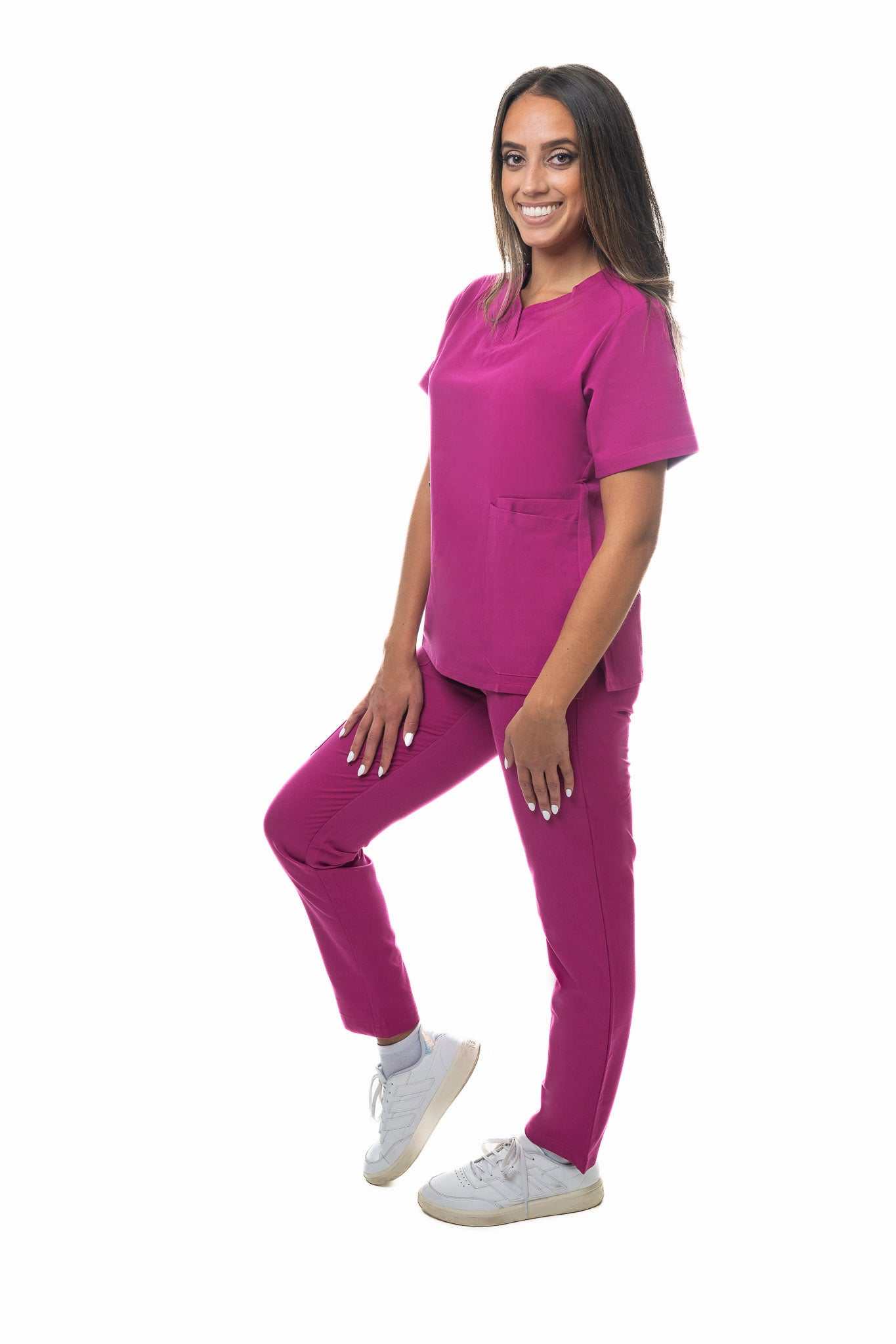 Woman wearing Zuena Rose Petal scrub pants with elastic waistband and multiple pockets, styled for comfort and durability