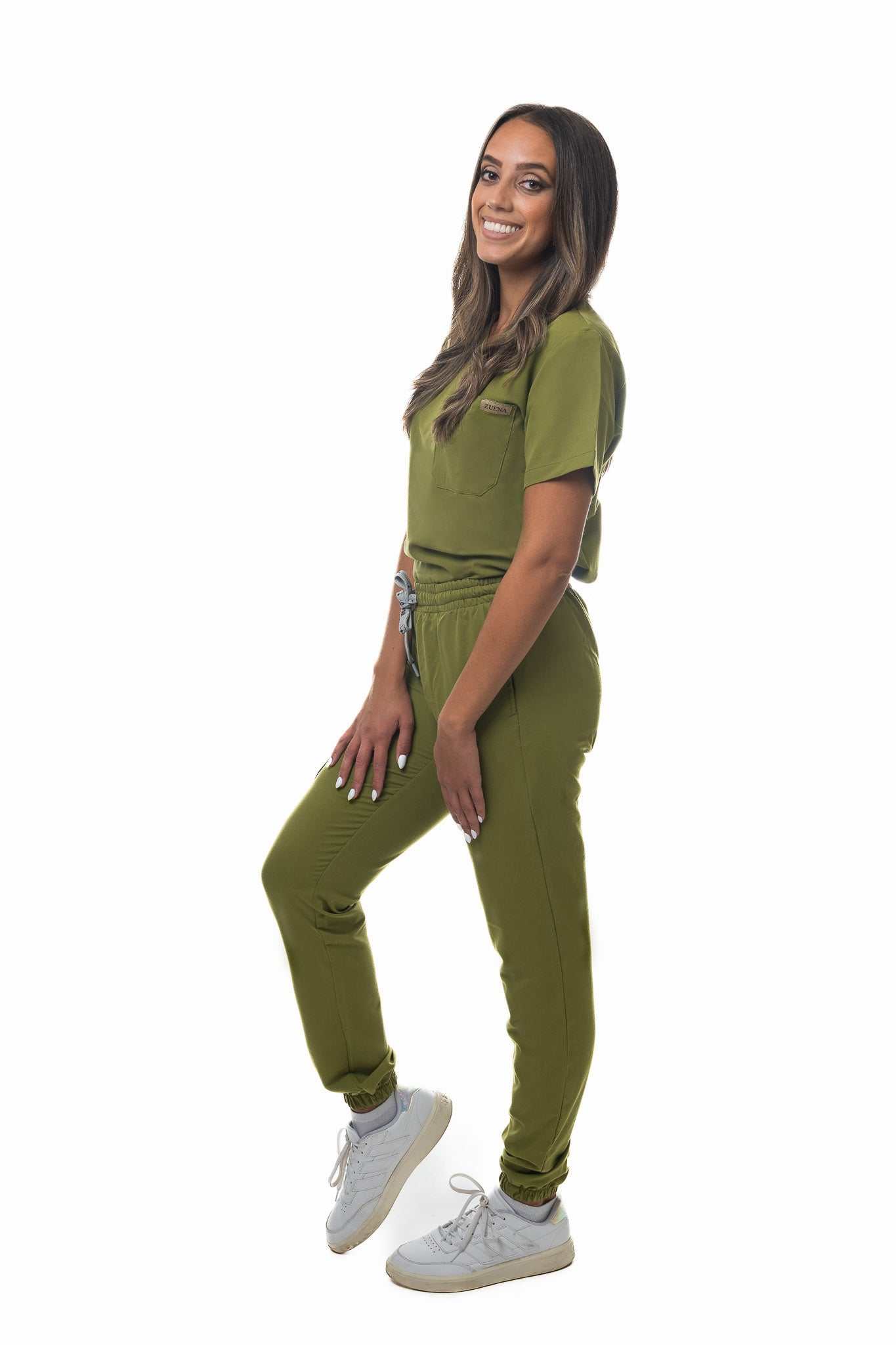 Woman wearing Zuena Olive Grove scrub pants and top in olive green with elastic waistband and five pockets