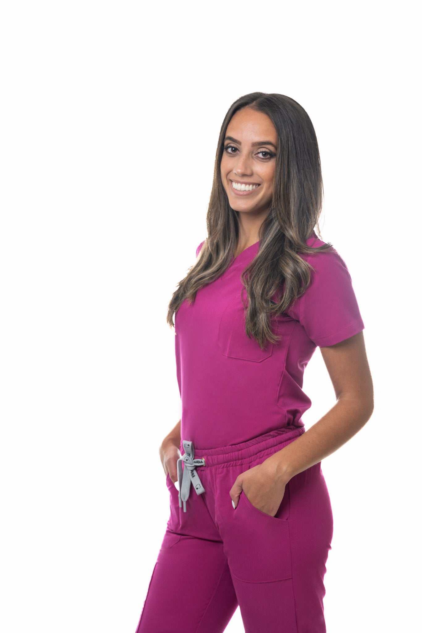 Woman wearing Zuena Rose Petal Scrub Pants in pink with elastic waistband and multiple pockets for comfort and durability