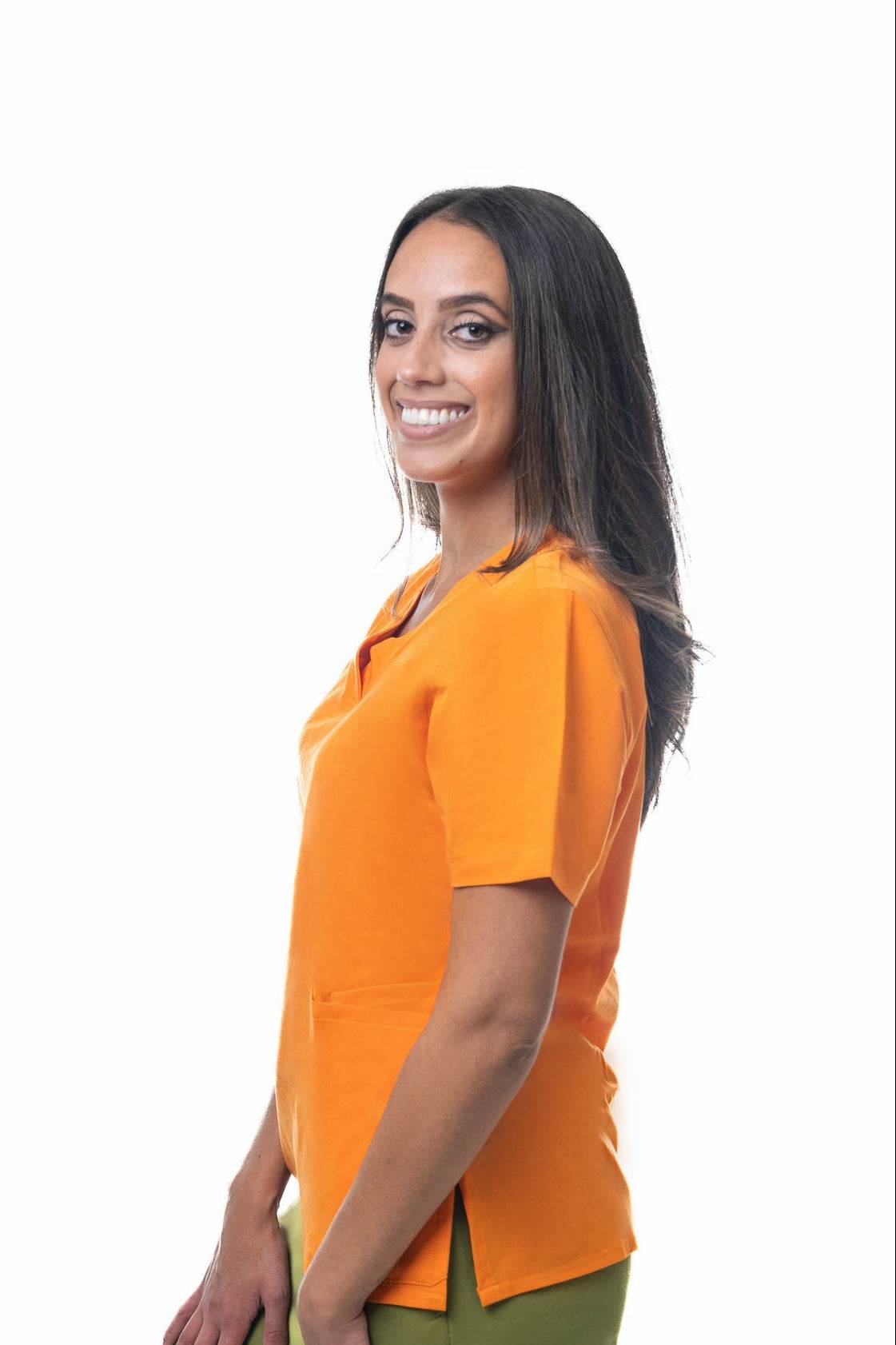 Woman wearing bright orange Zuena Tangerine Dream scrub top with short sleeves and side vents, smiling in profile.