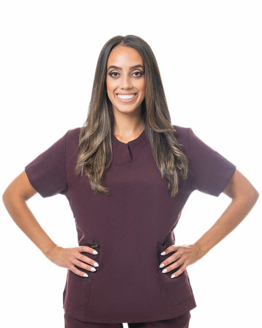 Woman wearing Zuena Burgundy Bloom scrub top with curved neck collar and three pockets