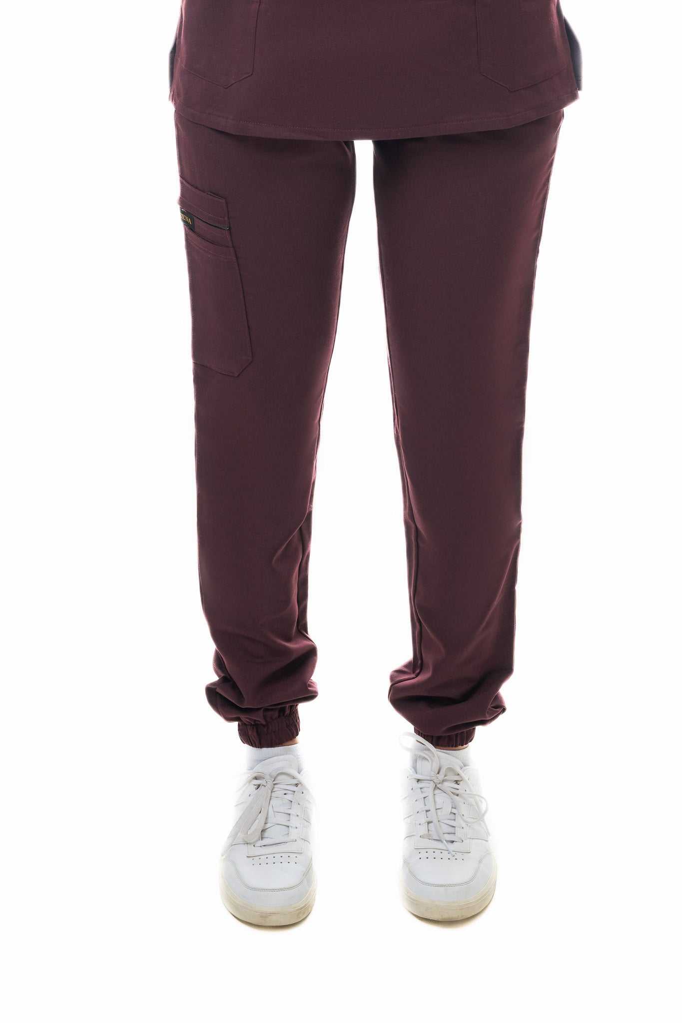 Maroon pants worn with white sneakers on a white background